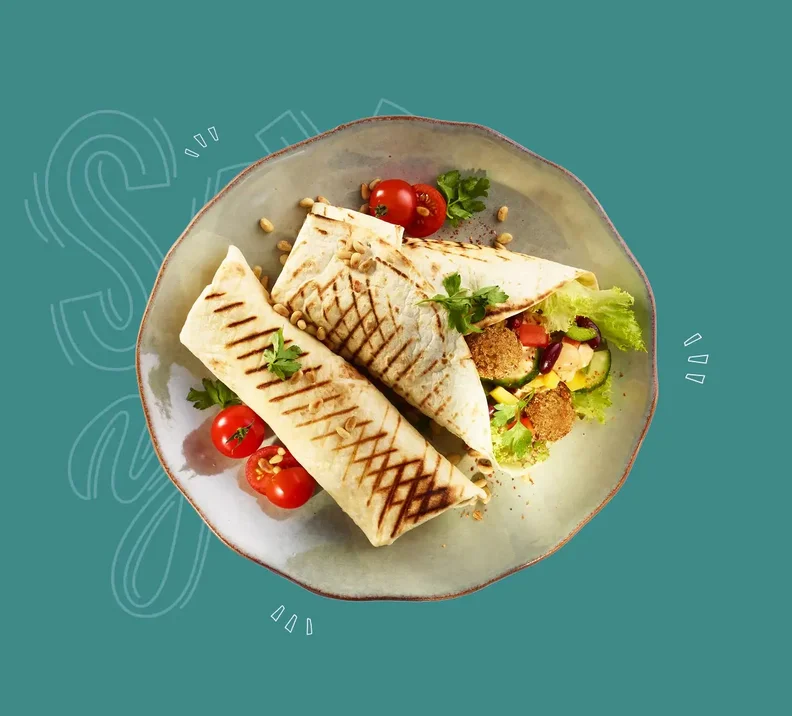 Falafel-Wrap mit Blattsalaten, Tomaten, Gurken, Bohnen, Mais, Peperoni/Paprika und Pinienkernen